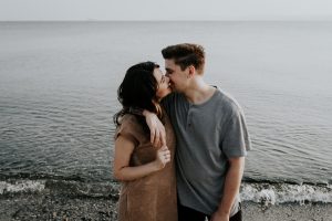 A couple kisses each other in front of the water. They are feeling happy after starting marriage counseling in Atlanta, GA with Faith and Family Empowerment.