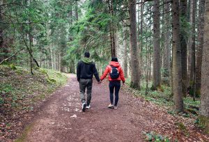 A couple hold hands as they hike through a forest. An online therapist in Decatur, GA can offer support from just about anywhere. We offer relationship therapy in Atlanta, GA, black marriage counseling in Decatur, GA, and other services! 30030