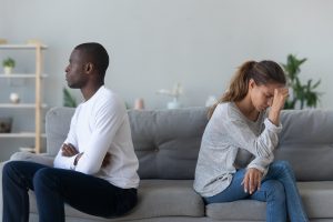 Image shows a couple sitting, facing away from each other while looking upset. This image could represent a couple regretting not beginning marriage counseling in Decatur, GA with a marriage counselor. 30030 | 30031