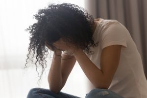 A woman sits with her head in hands, very. She has realized that it's time to begin online therapy in Georgia. She knows of an online therapist in Decatur, GA that can help. She is starting online therapy with Faith and Family Empower Counseling in Georgia. 