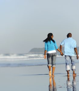 A couple walks on the beach holding hands. They are happy since they have started counseling for affair recovery in Atlanta, GA with Faith and Family Empowerment.