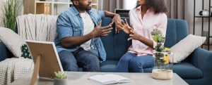 A couple talk with one another while sitting on a couch. This could represent the struggles of overcoming infidelity that affair recovery in Atlanta, GA can address. Contact an online therapist in Atlanta, GA to learn more about realtionship therapy in Atlanta, GA and other services.