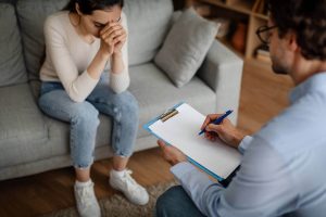 A person writes notes on a clipboard while sitting across from an upset woman. Learn how grief counseling in Atlanta, GA can offer support by contacting an online therapist in Atlanta, GA today.