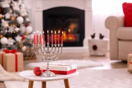 Shows a menorah on a table in front of a Christmas tree. Represents how a couples therapist in atlanta, ga can help navigate your interfaith relationship near the holidays.