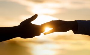 Shows people holding hands in front of a sunset. Symbolizes how a christian counselor in atlanta, ga can help you with spiritual intimacy.