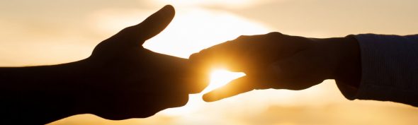 Shows a couple holding hands in front of a sunset. Represents how working with a christian therapist in atlanta, ga will help married couples deepen their spiritual intimacy.