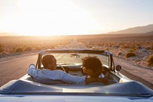 Shows a couple in a convertible and smiling on each other. Represents how marriage counseling in decatur, ga wants to support you and your spouse going on vacation together to spend time together.