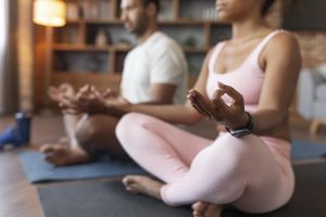 Black couple doing yoga together in their home representing someone practicing self care in Decatur, GA.