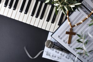 Photo of sheet music, a cross necklace and a microphone representing how music, including Christian hymns, can be soothing and calming when you're coping with anxiety. If you're looking for an anxiety therapist in the Atlanta area, I offer online anxiety counseling.