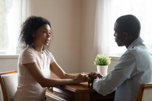 Shows a couple holding hands and talking. Represents how black marriage counseling supports couples via couples therapist in atlanta, ga.