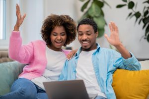 Shows an excited couple on their computer. Represents how online therapy in georgia helps black couples connect with a couples therapist in atlanta, ga. Search for "black marriage counseling" to learn more!
