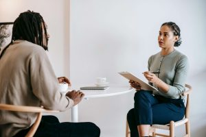 Two individuals seated at a round white table, engaged in a thoughtful conversation. Ideal for a blog on EMDR therapy in Atlanta and affair recovery in Atlanta, GA, offering support and healing after betrayal.