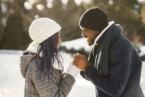 A joyful Black couple dressed in winter clothing holding hands and smiling at each other outdoors, symbolizing emotional healing through affair recovery in Atlanta, GA and support from EMDR therapy in Atlanta.
