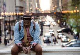 Man sitting on a concrete barrier in an urban setting, looking contemplative against a blurred cityscape with warm lights. Ideal for a blog on EMDR therapy in Atlanta and finding an EMDR therapist in Atlanta to heal from betrayal and feelings of inadequacy.