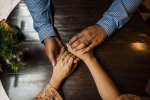 A couple holding hands across a table with wedding rings visible, symbolizing connection and commitment during marriage counseling in Decatur, GA with a marriage counselor in Atlanta, GA