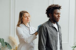 A doctor examines a young Black man with a stethoscope, representing the importance of addressing physical health when rebuilding intimacy with support from affair counseling atlanta and christian counseling in decatur, ga.
