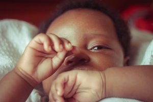 A Black newborn baby rests on a white blanket with tiny hands raised, representing the beautiful new season that a marriage counselor decatur ga and marriage intensive decatur at Faith and Family Empowerment can help couples navigate together.