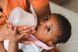 A Black baby is bottle fed by a parent in a tender close-up moment, representing the demanding realities of the parenting season that couples counseling decatur and marriage intensive decatur at Faith and Family Empowerment can help couples navigate together.