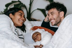 A young Black couple gazes at eachother with their newborn in a warm home setting, representing the emotional safety and connection that marriage counseling in decatur, ga can help couples protect during the parenting season.